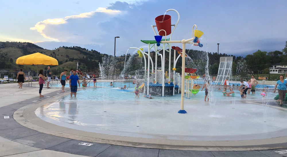 Horace Mann Park's outdoor wading pool with zero depth beach entry and a play structure featuring dumping buckets and spray features 